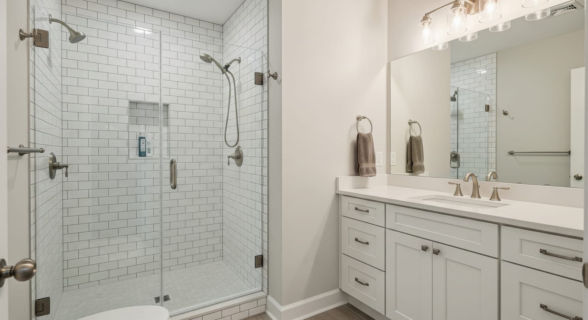 Modern bathroom with fresh tile, glass shower enclosure, and vanity